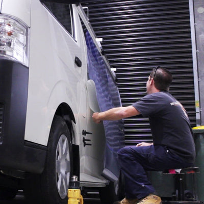 Application of coloured vinyl wrap graphics to the side of a work van, custom design in blue