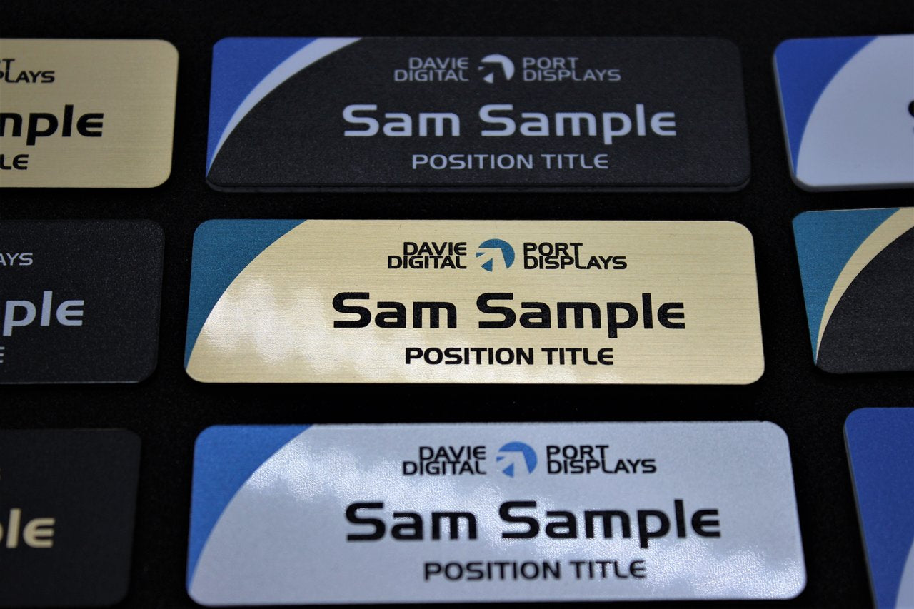 75x25mm Name badge in white plastic, brushed gold and silver finish. Colour printing with company names and logos