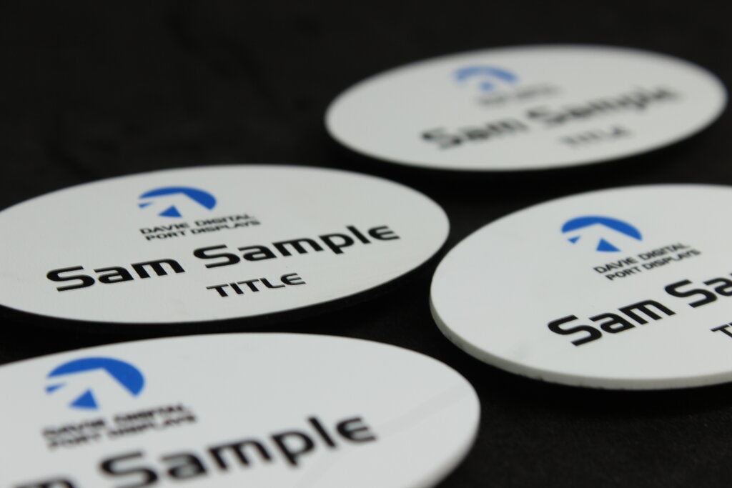 White oval plastic name badges in diffrent formats with company name logo and personalised design in coloured print